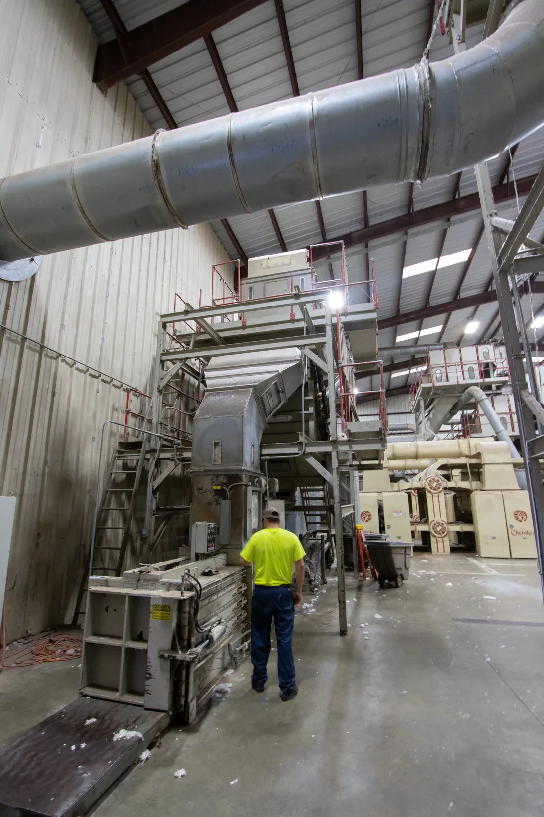 Worker inside a factory with industrial ducts and machinery