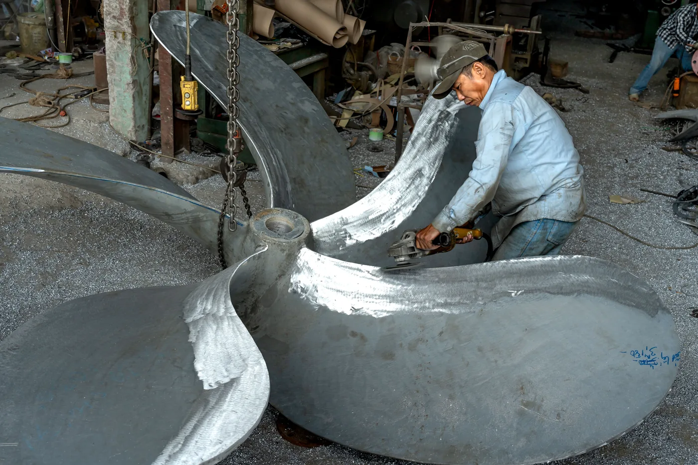 Industrial worker fabricating a large metal fan propeller